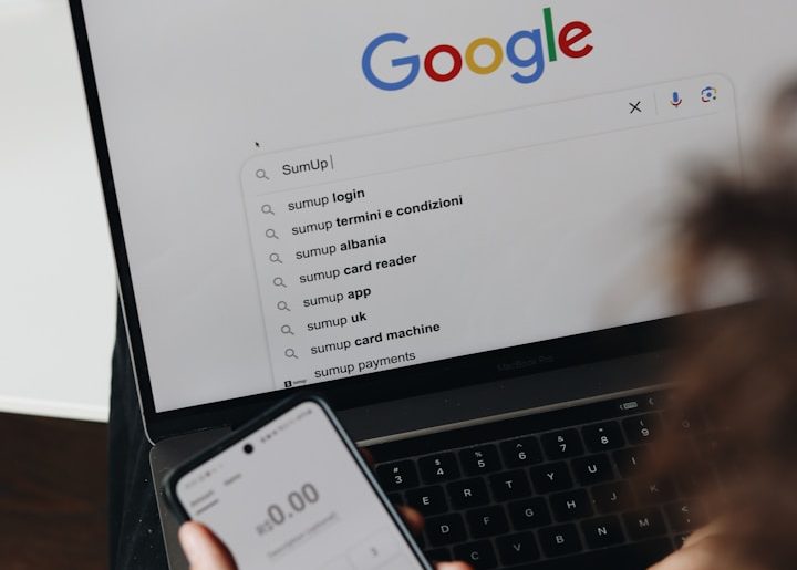 google Person nutzt ein Smartphone und einen Laptop mit Google-Suche im Vordergrund bei Namensentwicklung.