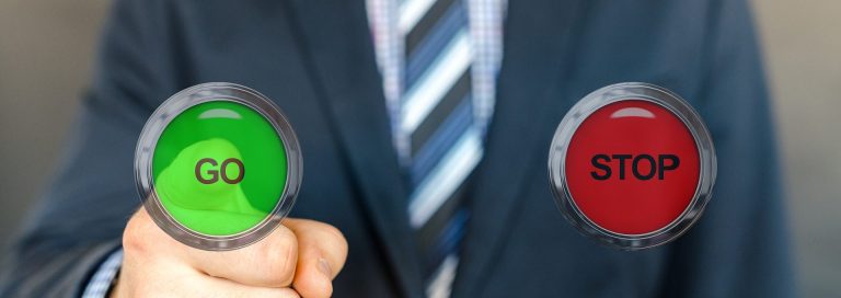 go Ein Mann einer Namensagentur im Anzug hält grüne „GO“- und rote „STOP“-Schilder in den Händen.