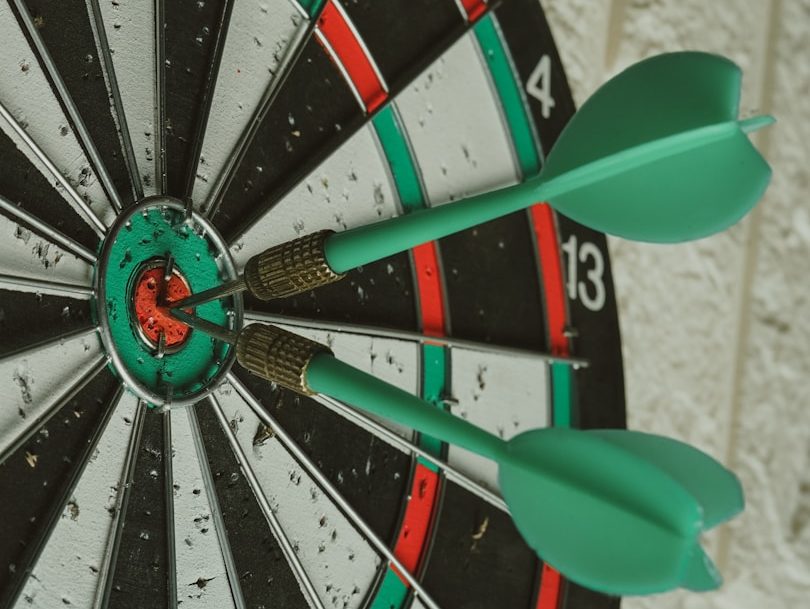 dart Zwei grüne Darts stecken im roten Zentrum einer Dartscheibe für Markennamen finden.